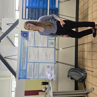 Student standing by their research poster during CRREATE.